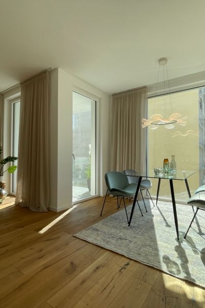 Großzügiges Wohnzimmer mit bodentiefen Fenstern, edlem Holzboden und stilvoller moderner Einrichtung